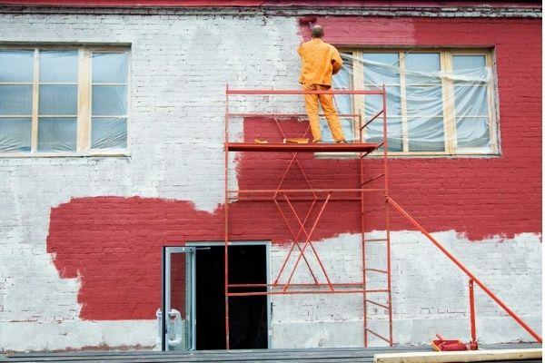 exterior brick painter with ladder and red paint