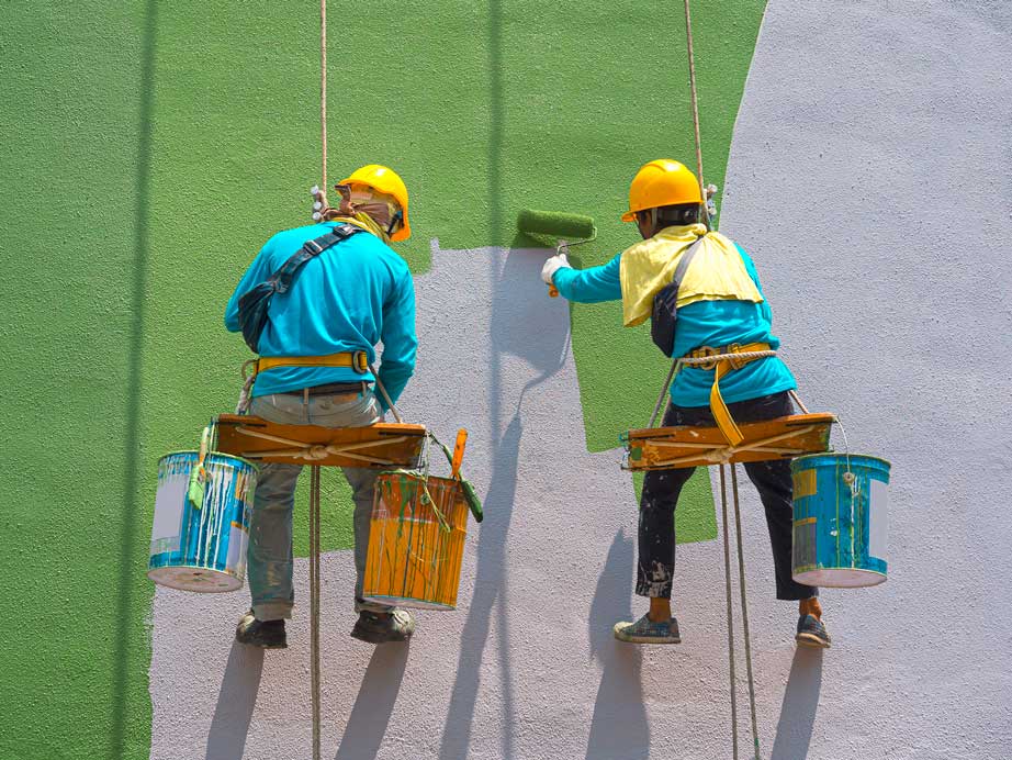 two strata painters with brushes abseiling on building